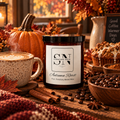 A jar candle labeled 'Autumn Roast' by Signature Note Candle Co. is styled on a rustic wooden table with fall-themed props including a pumpkin, cinnamon sticks, coffee beans, a mug of latte art coffee, and a muffin in a cozy indoor setting.